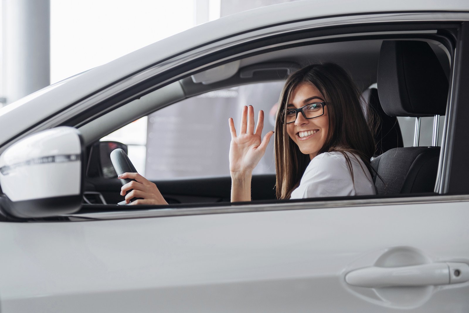 Pretty young woman driving new car. Mujer-con -licencia-de-conducir